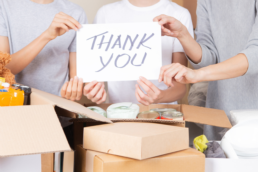 Thank You for Donation. Volunteers Collecting Donations for Charity. Teenagers and Woman Hands Holding Paper Sheet with Message Thank You over Cardboard Boxes Full of Food Glocery, Clothes, Toys